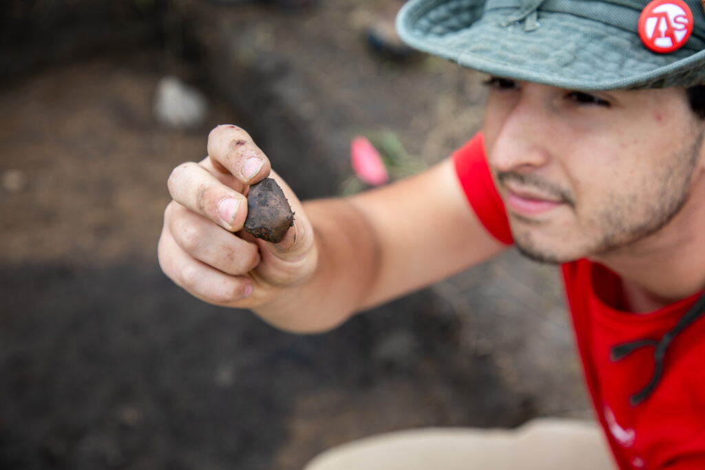 BoydFS graduate holding the elbow of an 800-year-old pipe he found in a midden. 