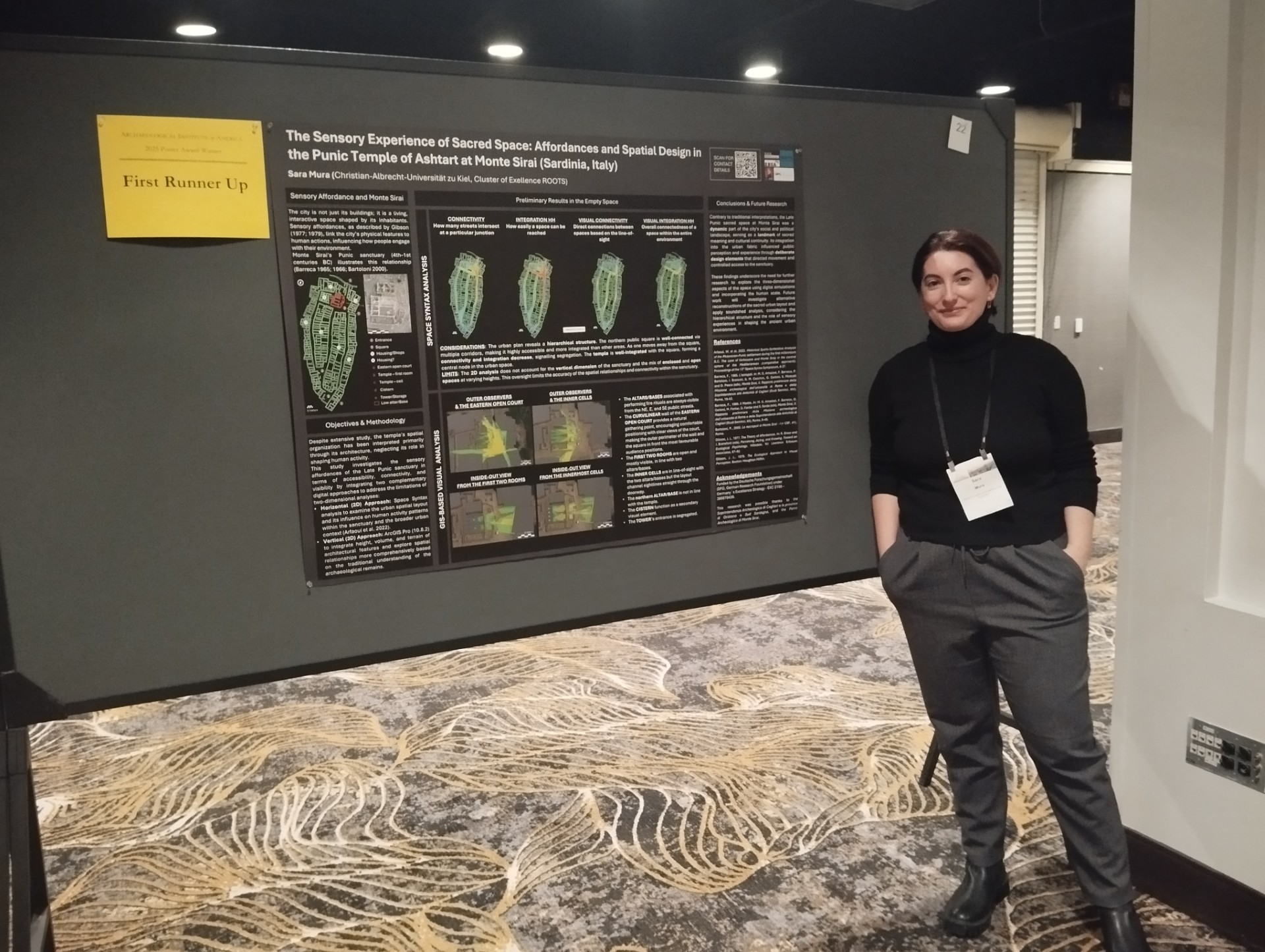 An image of Sara Mura standing next to her poster at the annual meeting with the First Runner-Up notice pinned beside it. 